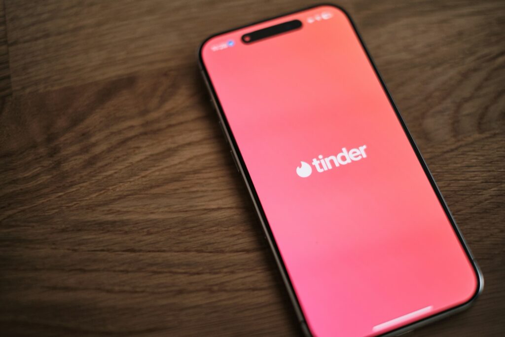 Tinder, AI 기능 도입으로 사용자 경험 혁신 시도 A pink iPhone sitting on top of a wooden table